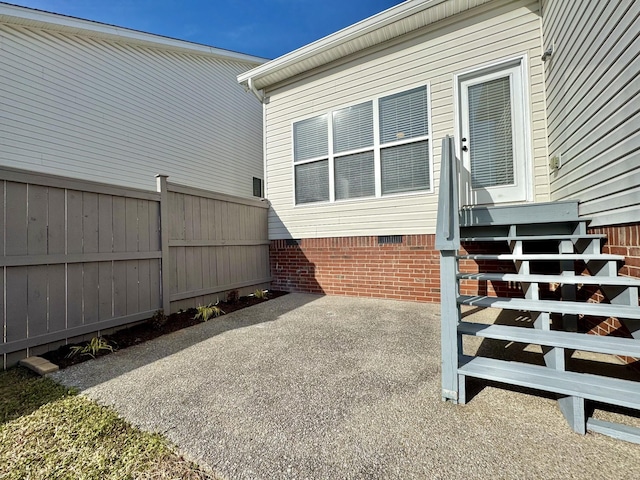 view of side of property featuring a patio, crawl space, and fence