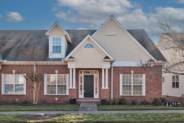 view of front of house with brick siding and roof with shingles