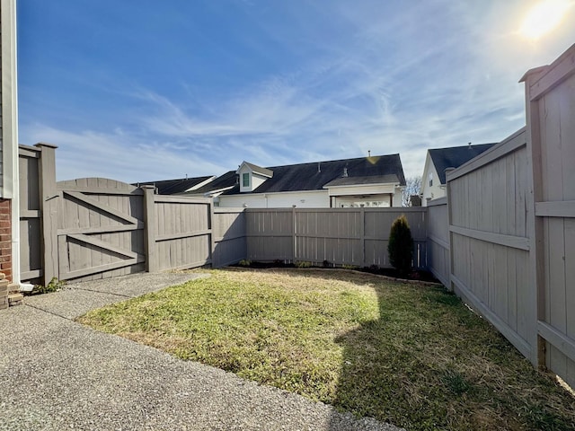 view of yard with a fenced backyard and a gate