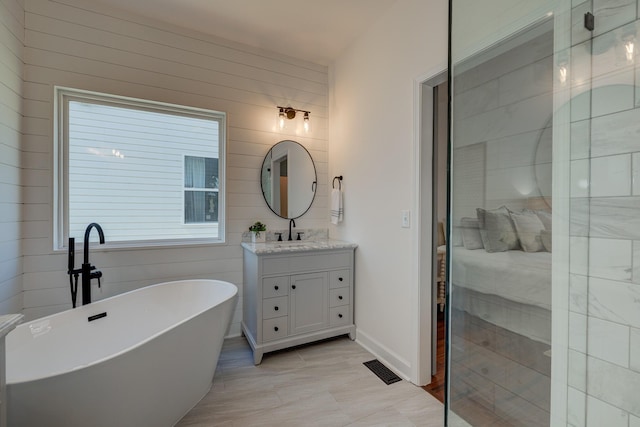 full bath with a soaking tub, visible vents, vanity, and baseboards