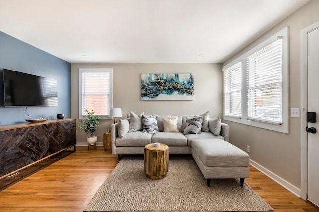 living area featuring baseboards and light wood finished floors