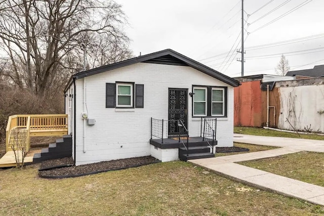 bungalow featuring a front yard and brick siding