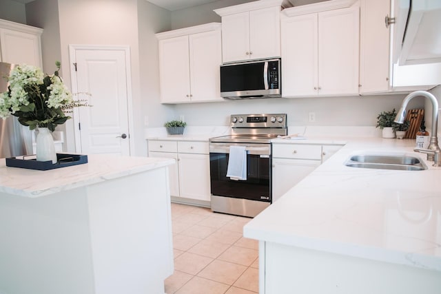 kitchen with light tile patterned floors, white cabinetry, appliances with stainless steel finishes, and a sink