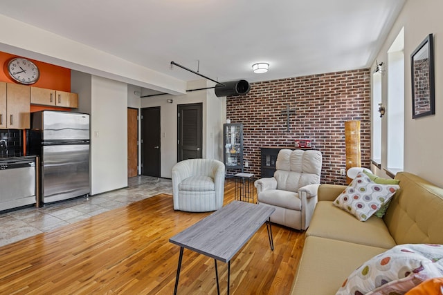 living room featuring brick wall and light wood-type flooring