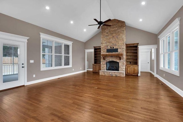 unfurnished living room featuring plenty of natural light, a fireplace, baseboards, and wood finished floors