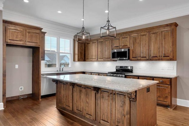 kitchen featuring stainless steel appliances, dark wood-type flooring, a kitchen island, a sink, and backsplash