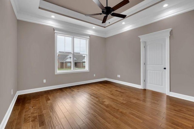 unfurnished room featuring baseboards, a tray ceiling, and wood finished floors