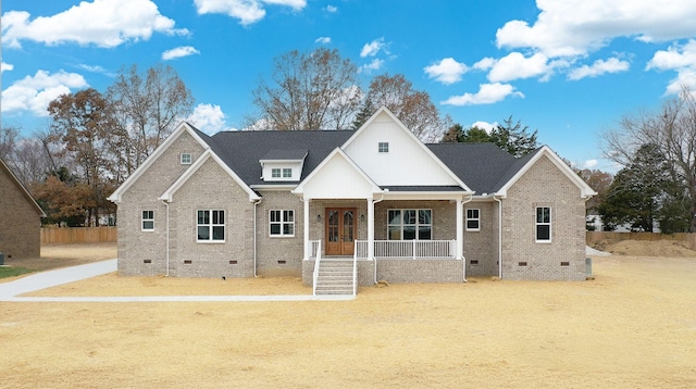 view of front facade with a porch, crawl space, brick siding, and roof with shingles