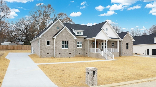 view of front of home with a porch, crawl space, fence, and brick siding