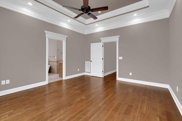 spare room featuring baseboards, a raised ceiling, wood finished floors, crown molding, and recessed lighting