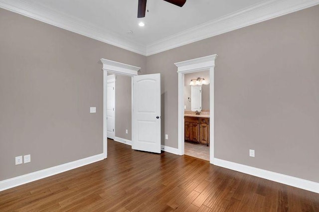 empty room with ornamental molding, a sink, ceiling fan, wood finished floors, and baseboards