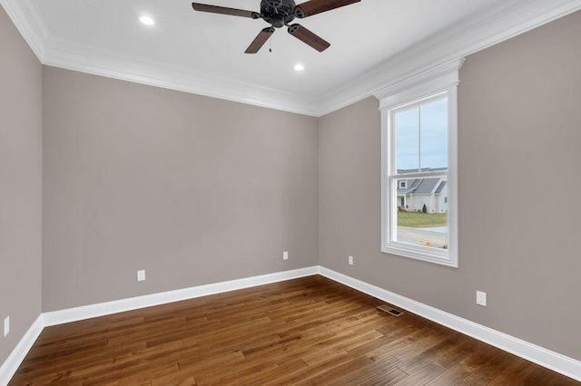 spare room featuring baseboards, visible vents, a ceiling fan, dark wood-style flooring, and crown molding