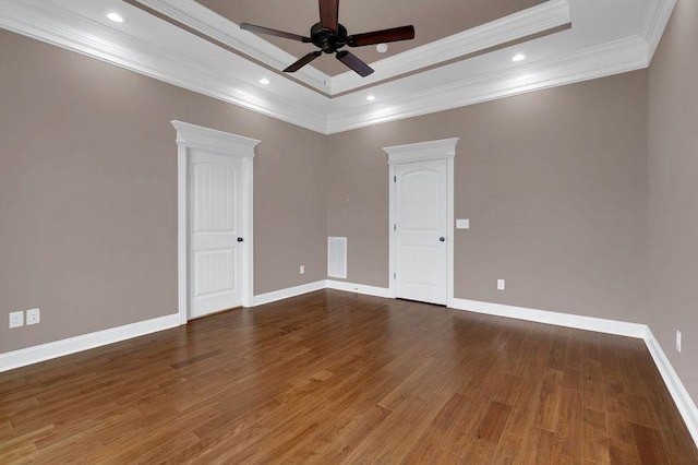 empty room with baseboards, a raised ceiling, wood finished floors, and recessed lighting