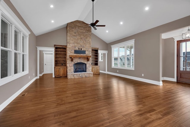 unfurnished living room with a fireplace, visible vents, dark wood-style flooring, and ceiling fan with notable chandelier