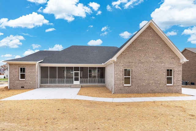 back of house with brick siding, a shingled roof, a sunroom, crawl space, and a patio area