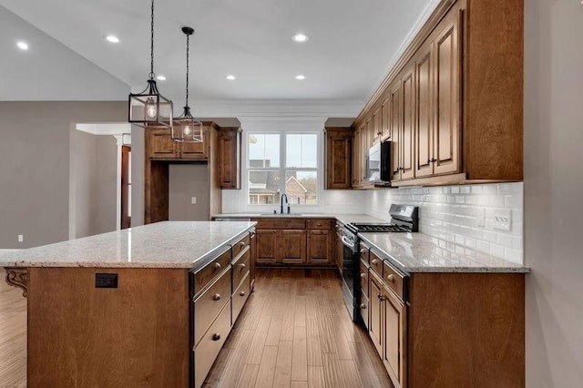 kitchen featuring a center island, stainless steel appliances, tasteful backsplash, wood finished floors, and light stone countertops