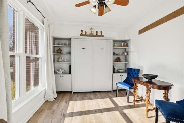 sitting room featuring ornamental molding, ceiling fan, and light wood-style flooring