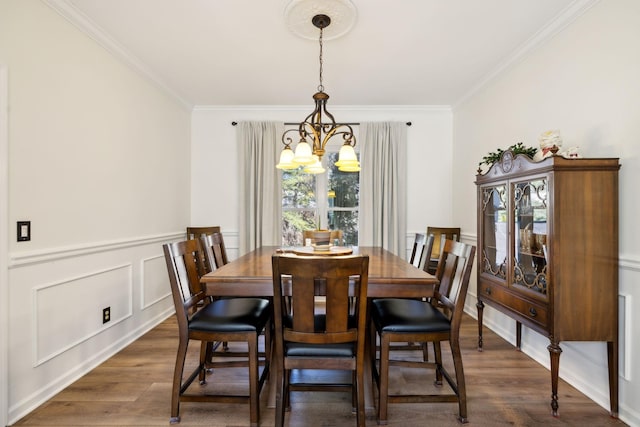 dining space featuring dark wood-style floors, a wainscoted wall, ornamental molding, a chandelier, and a decorative wall