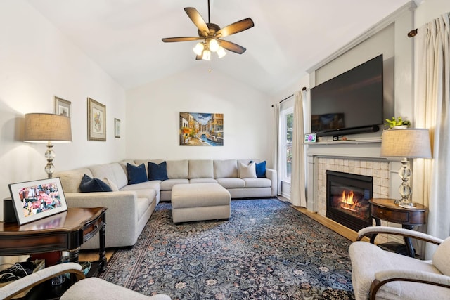 living room with wood finished floors, vaulted ceiling, a ceiling fan, and a tile fireplace