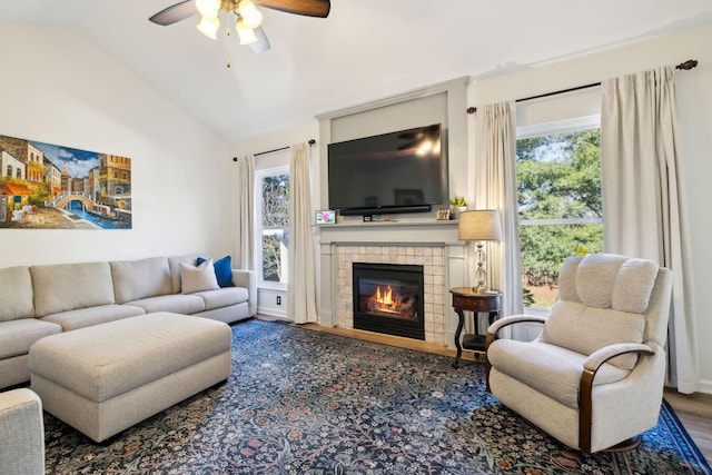 living room featuring a ceiling fan, vaulted ceiling, wood finished floors, and a tile fireplace