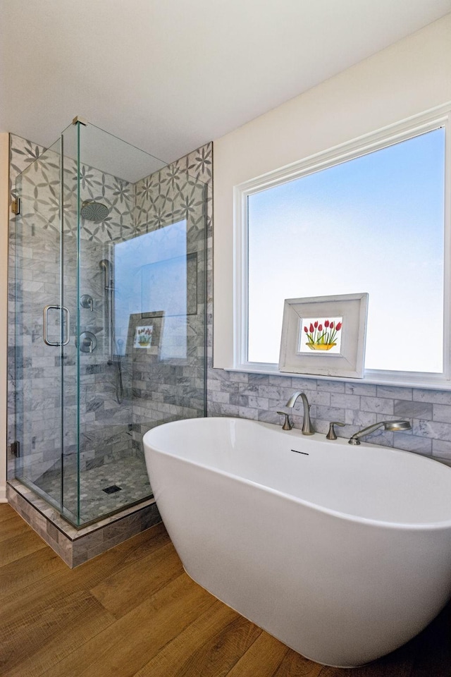 full bathroom with a stall shower, a soaking tub, and wood finished floors