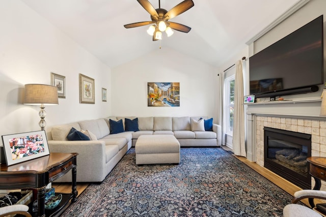 living area with a ceiling fan, vaulted ceiling, wood finished floors, and a tile fireplace