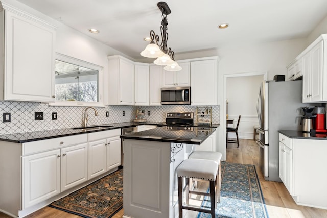 kitchen with appliances with stainless steel finishes, dark countertops, a sink, and white cabinets