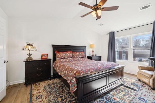 bedroom featuring lofted ceiling, baseboards, visible vents, and light wood finished floors