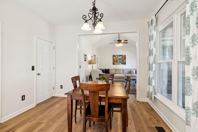 dining area featuring light wood finished floors, visible vents, baseboards, and vaulted ceiling