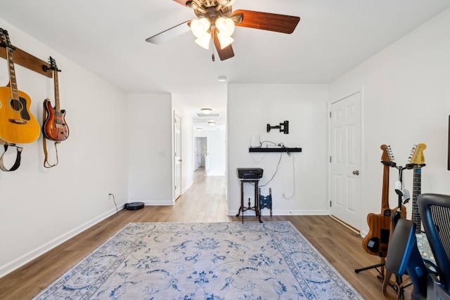 workout room featuring ceiling fan, wood finished floors, and baseboards