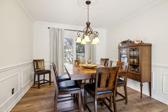 dining area featuring dark wood-style floors, a chandelier, ornamental molding, and a decorative wall