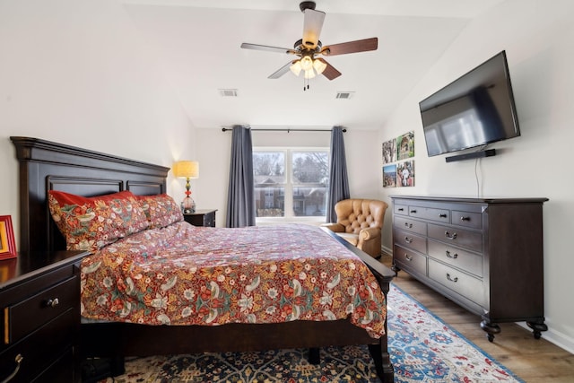 bedroom with visible vents, vaulted ceiling, baseboards, and wood finished floors