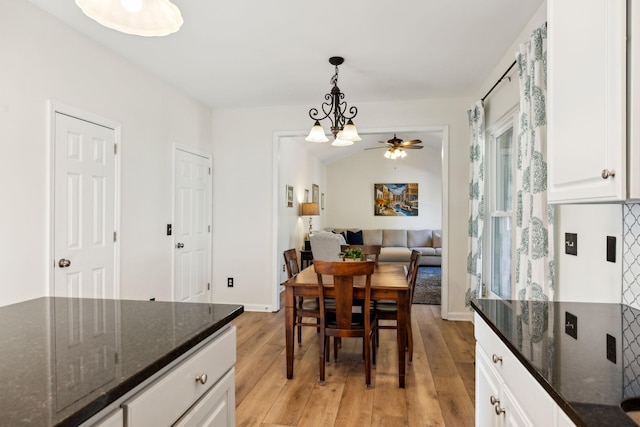 dining area with ceiling fan with notable chandelier, light wood-style flooring, and baseboards