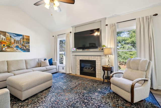 living area featuring ceiling fan, a fireplace, vaulted ceiling, and wood finished floors