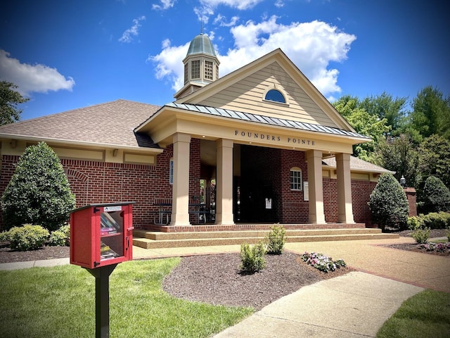 neoclassical / greek revival house featuring metal roof, covered porch, brick siding, a shingled roof, and a standing seam roof