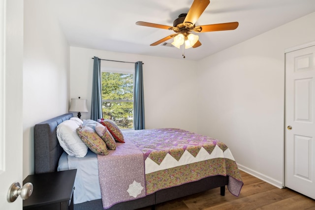 bedroom with ceiling fan, wood finished floors, and baseboards