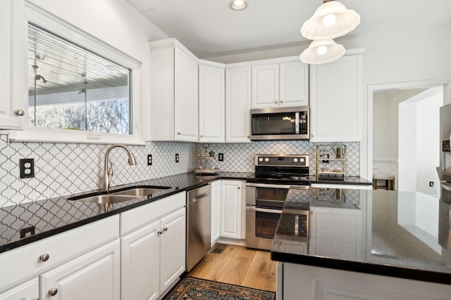 kitchen featuring appliances with stainless steel finishes, backsplash, a sink, and white cabinets