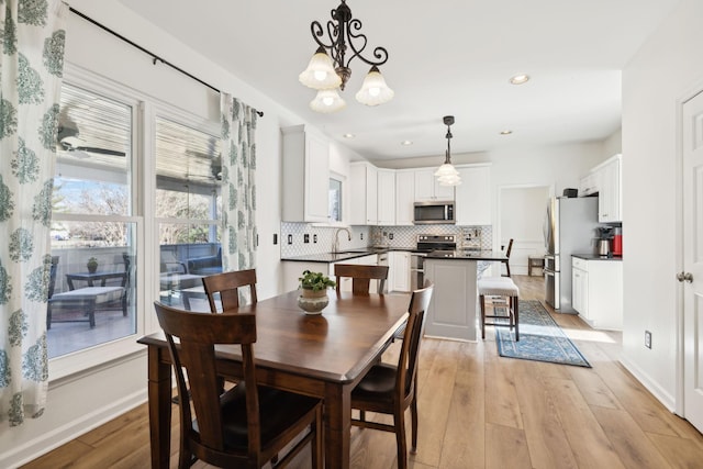 dining room featuring recessed lighting, light wood-style flooring, baseboards, and an inviting chandelier