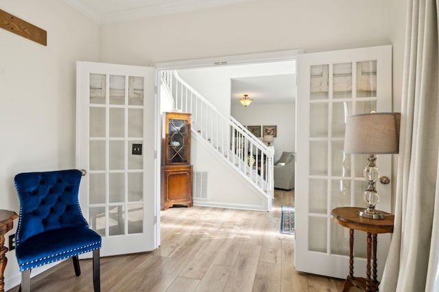 living area with wood finished floors, visible vents, stairs, ornamental molding, and french doors