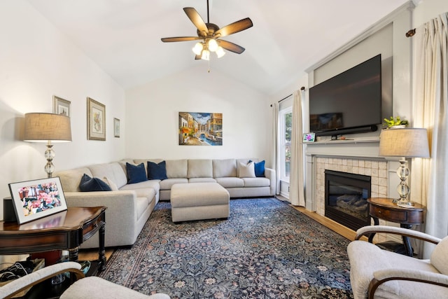 living room featuring a tile fireplace, wood finished floors, vaulted ceiling, and ceiling fan