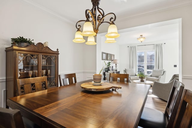 dining room with a notable chandelier, ornamental molding, and wood finished floors