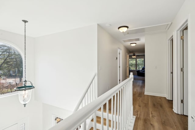 corridor featuring an upstairs landing, wood finished floors, visible vents, and baseboards