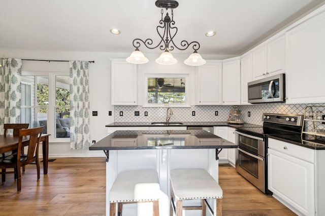 kitchen featuring stainless steel appliances, a sink, light wood-style flooring, and white cabinets