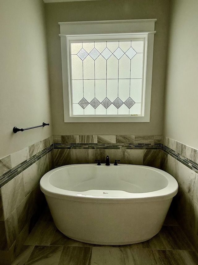 full bathroom with a wainscoted wall, tile walls, and a freestanding bath