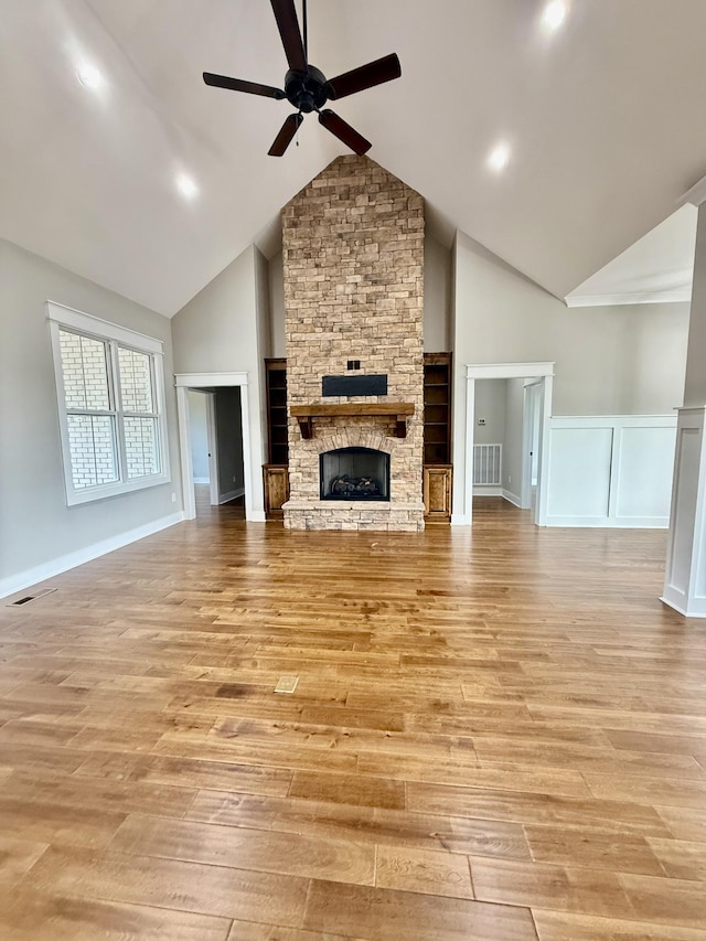 unfurnished living room with visible vents, light wood finished floors, a fireplace, and a ceiling fan