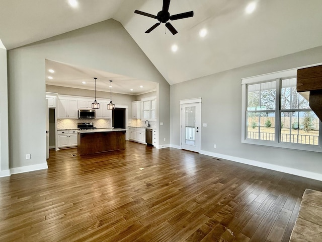 unfurnished living room featuring baseboards, a ceiling fan, dark wood-type flooring, high vaulted ceiling, and a sink