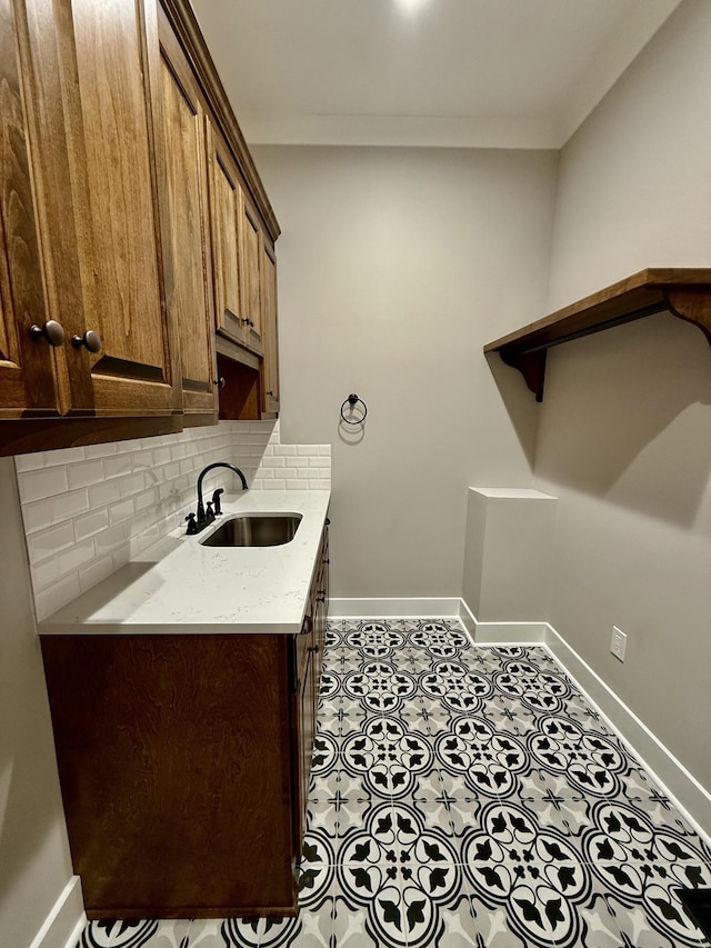 laundry area featuring crown molding, baseboards, a sink, and tile patterned floors