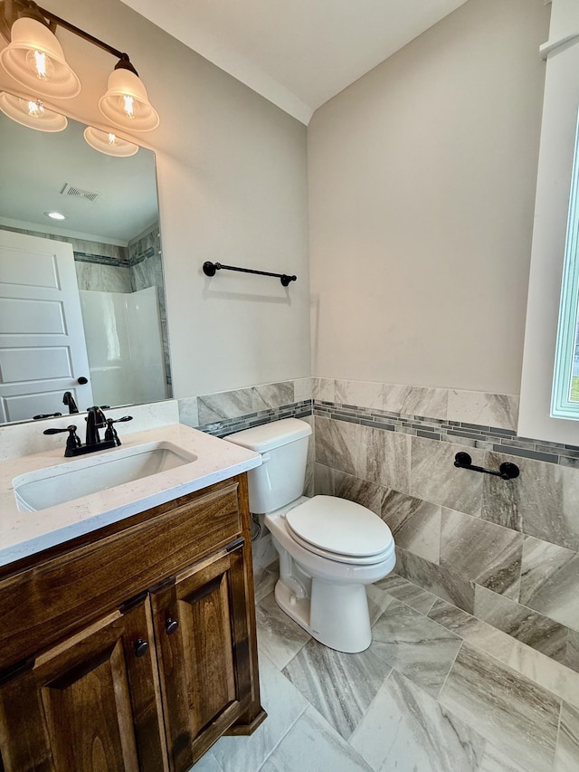 bathroom with a shower, tile walls, visible vents, toilet, and vanity