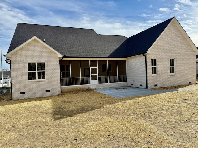 back of house with brick siding, a patio, a shingled roof, a sunroom, and crawl space