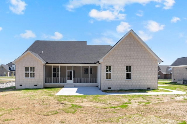 rear view of house featuring a patio area, brick siding, a lawn, a sunroom, and crawl space
